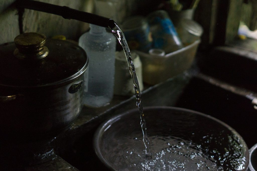 Water flowing into a metal bowl from a faucet.