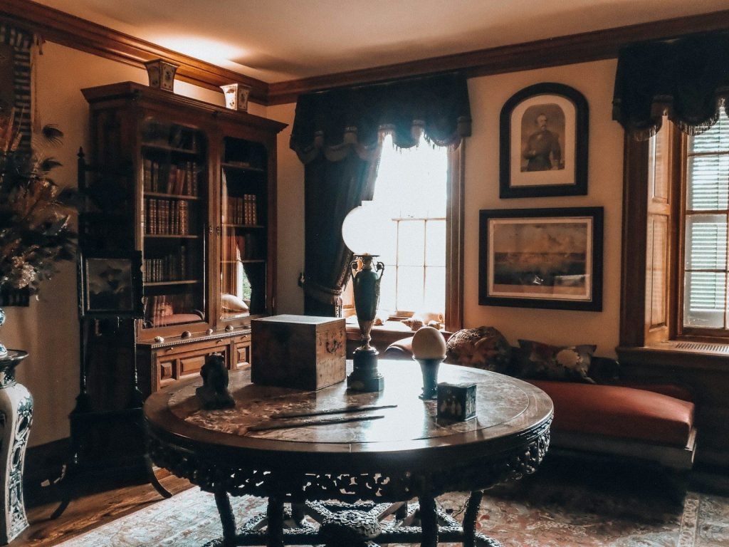Elegant antique room featuring a carved table and large bookshelf.