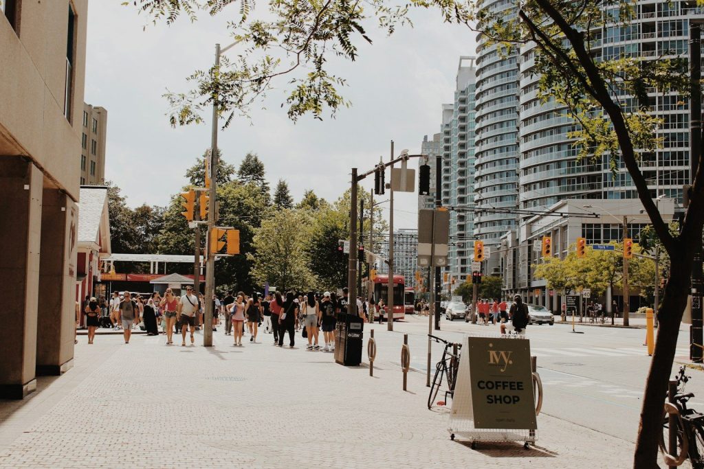 People walk on a busy city street with tall buildings.