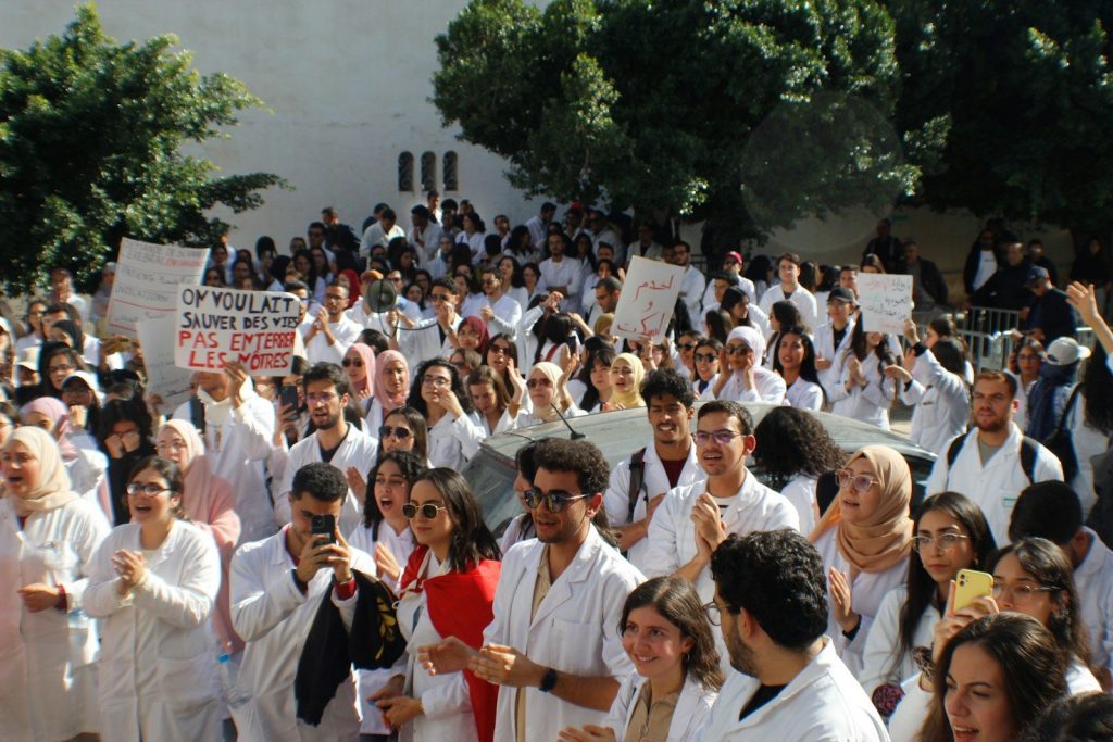 A large group of people in white coats are protesting.