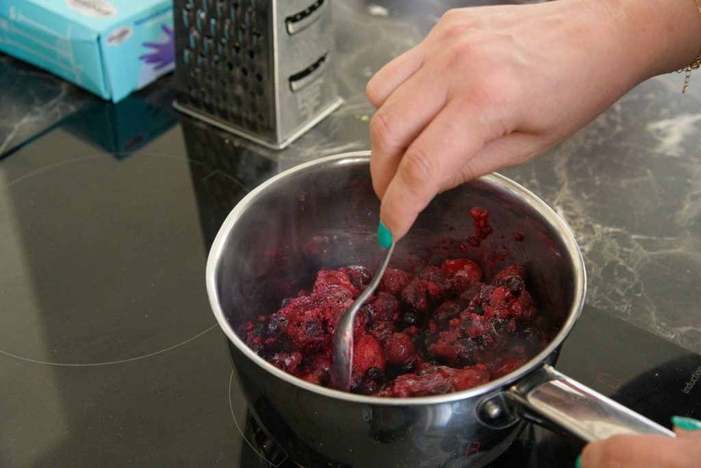 a person stirring a pot of food on a stove