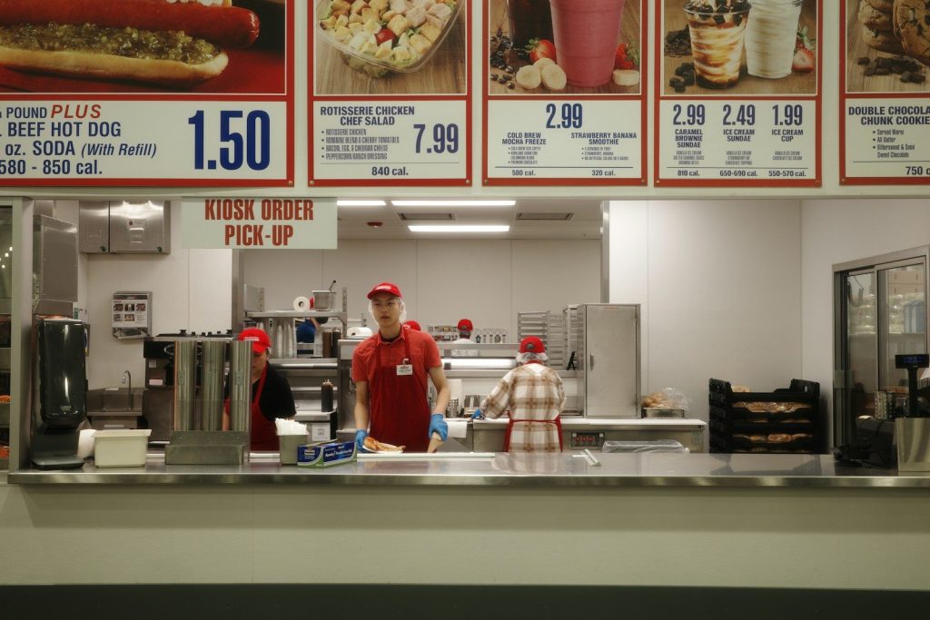 Food court workers behind a counter with menu boards.