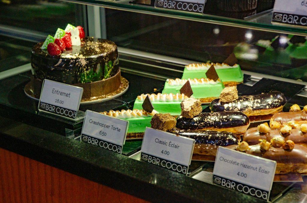 A display case filled with various cakes, pastries, and eclairs.