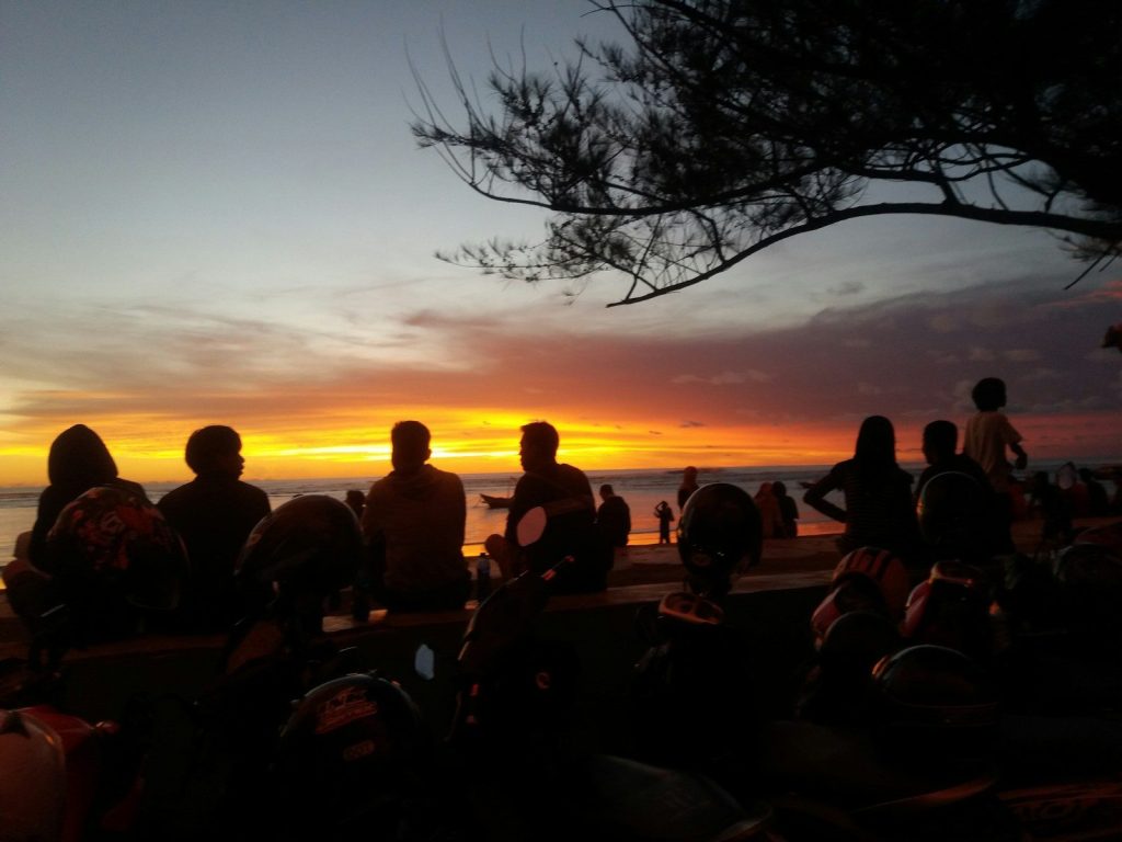 silhouette of people facing body of water