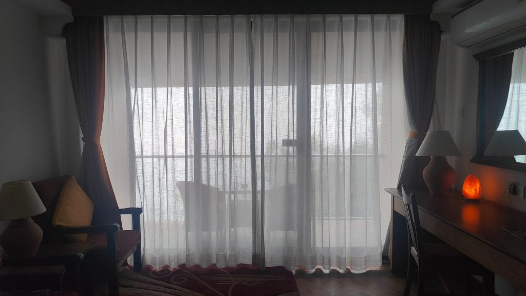 A hotel room with a bed, desk and television