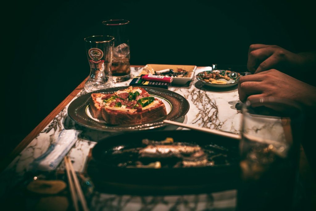 A table topped with a pizza and a plate of food