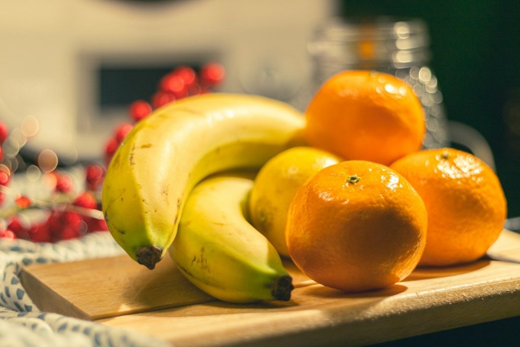 yellow banana fruit beside orange fruits