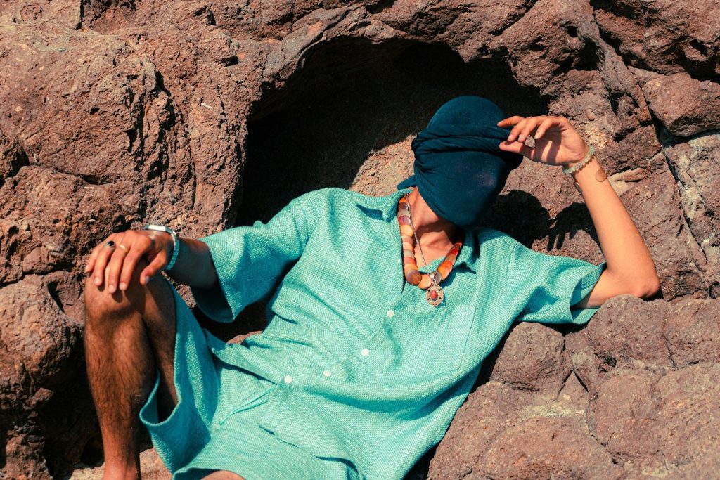 Person in teal outfit sits in rocky alcove