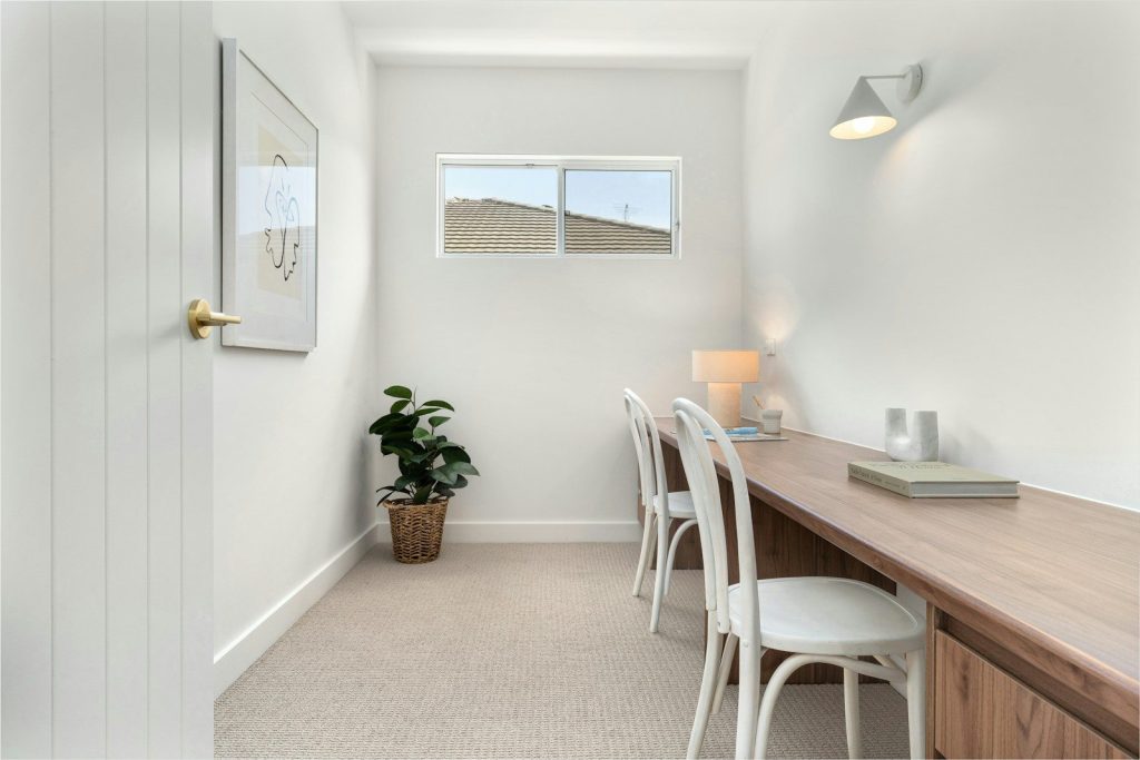 A room with a desk and chairs and a potted plant