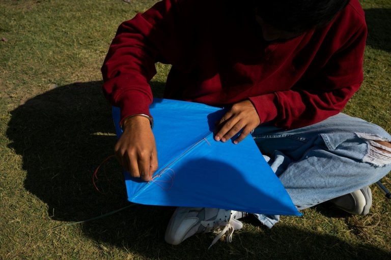 a man sitting on the ground holding a blue kite