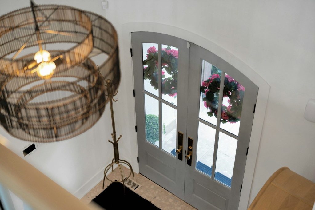Entryway with double doors, wreaths, and a large decorative chandelier.