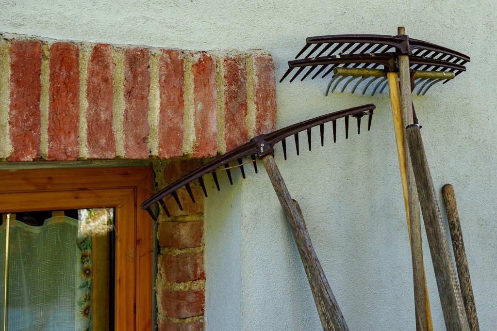 Two old rakes leaning against a wall.