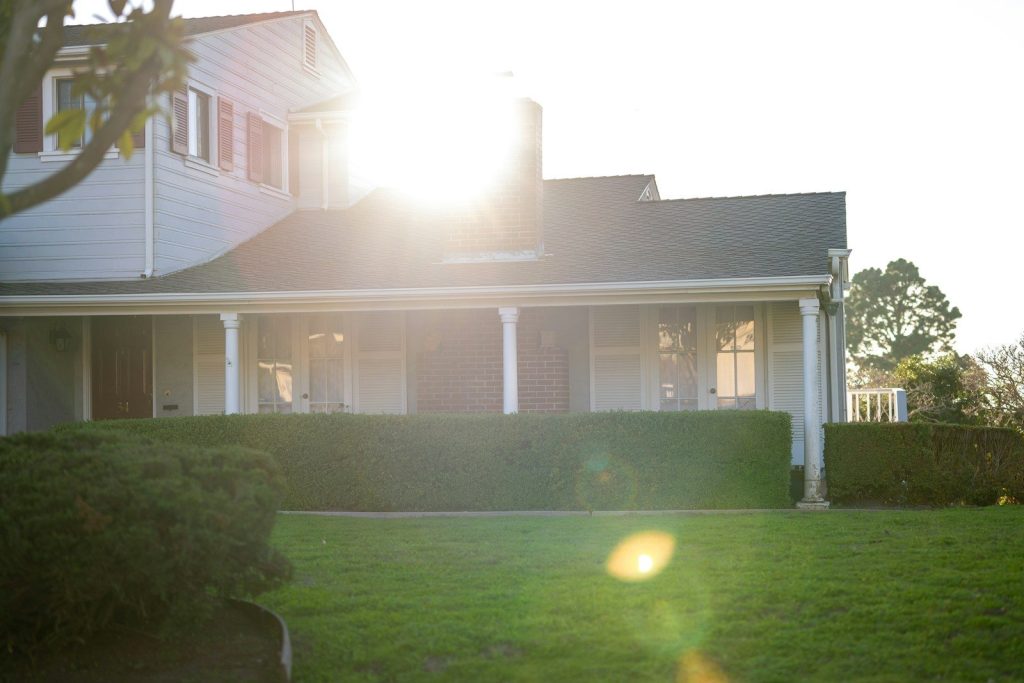 The sun shines brightly on a large white house