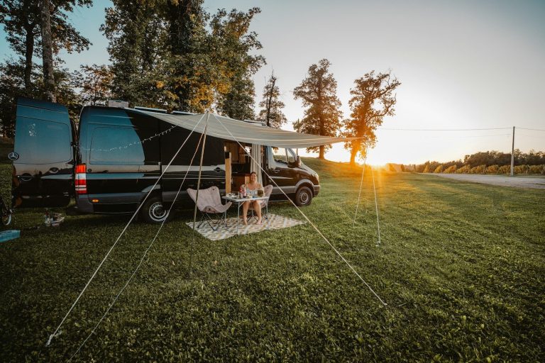 Couple relaxing under camper van awning at sunset