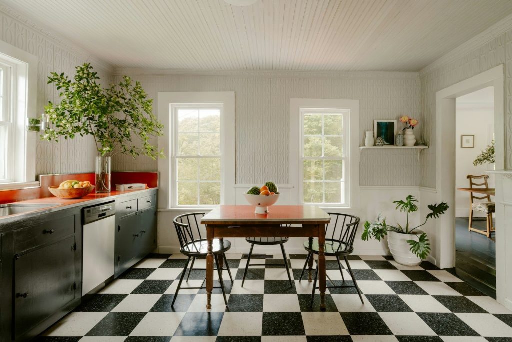Bright kitchen with checkered floor, dining table, and large windows.