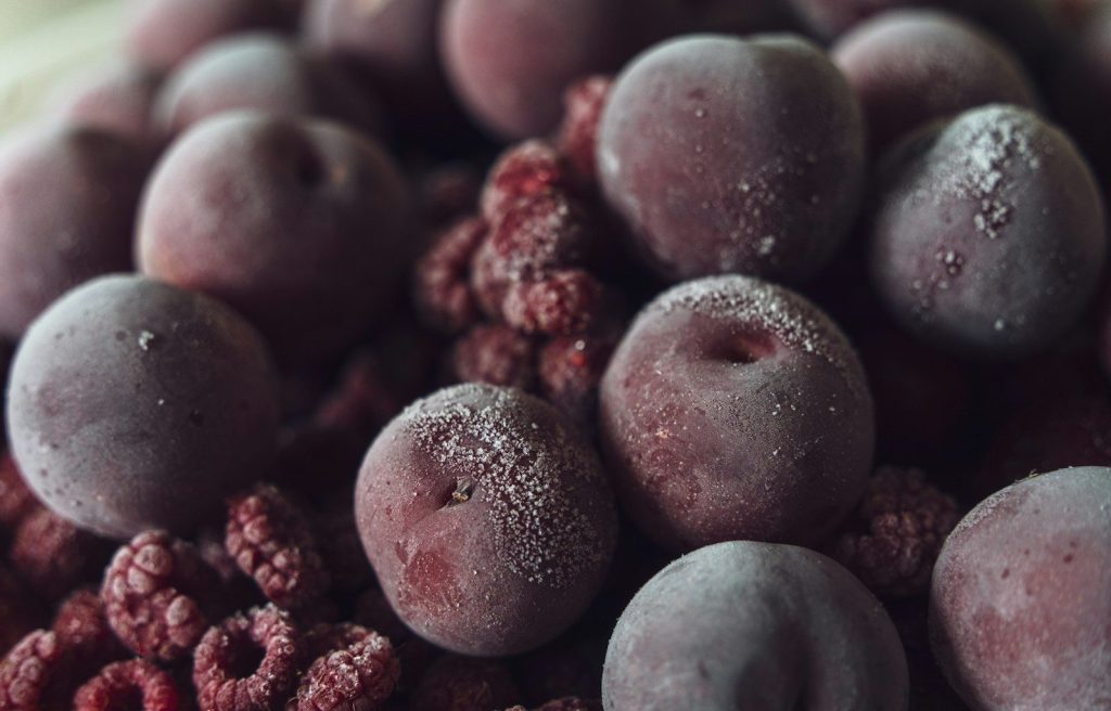 Frozen plums and raspberries with a dusting of frost.